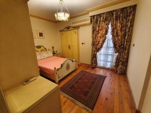 Un dormitorio con una cama y una ventana grande. en Legacy Lodge Heliopolis, en El Cairo
