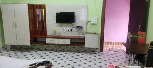 a room with a tv on a wall with a table at Maa Sumthira Lodge in Majuli