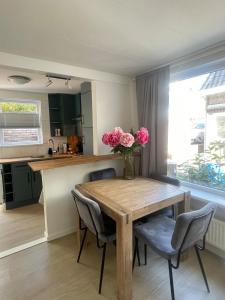 a kitchen with a wooden table with pink flowers on it at Wendy's Tiny Beachhouse in Noordwijk