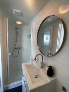 a bathroom with a sink and a shower with a mirror at Wendy's Tiny Beachhouse in Noordwijk +11 photos