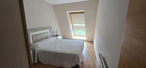 a small bedroom with a bed and a window at Ático Paraíso in San Ciprián