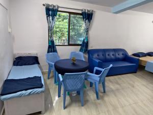 a room with a bed and a couch and a table and chairs at Krishna Garden and Resort in Betgaon