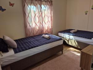 two beds in a room with a window at Къщички Sunrise in Tsarevo