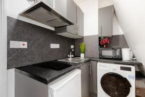 a kitchen with a sink and a washing machine at Nestio - Paddington Serviced Studios! in London