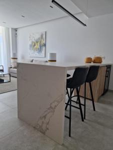 a kitchen with a white counter and two black chairs at ELEVENLIGHTS-COSTABALLENA Garden View in Costa Ballena +190 photos