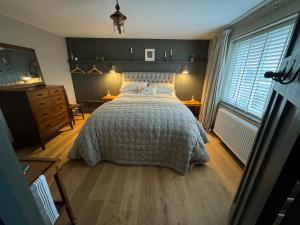 a bedroom with a large bed and two windows at Helvellyn Cottage in Penrith