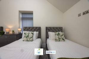 Un dormitorio con dos camas con sábanas y almohadas blancas. en 2 Bedroom Apartment By Green Haven Escapes Short Lets & Serviced Accommodation In Leeds with Free WiFi & Parking, en Farnley