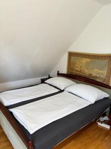a bed in a room with a painting on the wall at Bodza Vendégház in Balatonfüred
