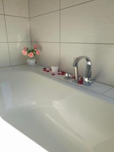 a bathroom sink with a faucet and flowers on a shelf at Ferienwohnung Lessing in Meißen