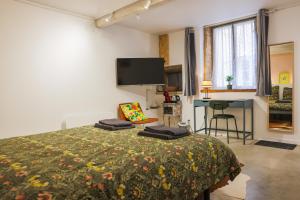 a bedroom with a bed and a desk and a tv at Maison de ville LAGALERIE in Tournus