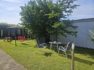 a yard with chairs and a table and a tree at Villa Viktoria Whg 11 - "Schwalbennest" in Kölpinsee