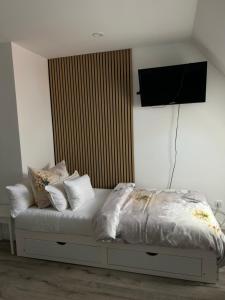 a white bed with pillows and a television on the wall at Zimmer mit Küche und Bad in Wedemark