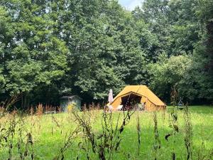 a yellow tent in the middle of a field at Glamping du Manoir de la Douve in Heuvelland