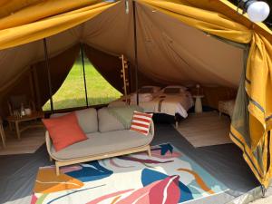 a tent with a couch and a bed in it at Glamping du Manoir de la Douve in Heuvelland