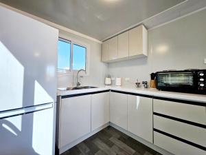 a white kitchen with a sink and a microwave at Tiny Cottage by the Lake in Waranga +19 photos