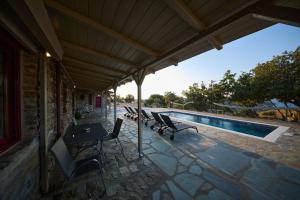 a patio with chairs and a table and a pool at Petra Vista Retreats in Otzias