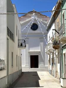an alley with a white building with a string of lights at Il Maestralino, nice apartment with courtyard in Calasetta