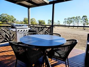 a table and chairs on a deck with a grill at Tiny Cottage by the Lake in Waranga