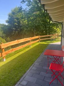 a red table and chairs on a patio with a fence at Ferienwohnung Vita-Natura in Eppenbrunn