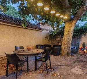 une table et des chaises assises sous un arbre dans l'établissement Loft SSL insolite!!!, à Gignac-la-Nerthe
