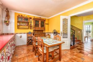 a kitchen with yellow walls and a wooden table and chairs at La Casa Del Maestro in Estepona +21 photos