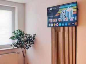 una televisione su un muro in una stanza con una pianta di Bedroom with free parking a Borsdorf