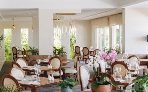 a restaurant with tables and chairs and plants at Hotel Corsica & Spa Serena in Calvi