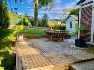 a wooden deck with chairs and a table in a yard at Magnifique Maison vue mer 150m de la plage in Trouville-sur-Mer