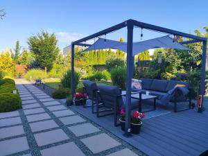 a pergola with a couch and chairs on a patio at Visit Poznan in Dąbrówka