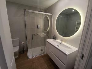 un bagno con lavandino e doccia con specchio di Apartamentos BONDELA a Madrid