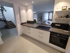 a kitchen with white cabinets and a staircase in the background at Luna in Laudenbach