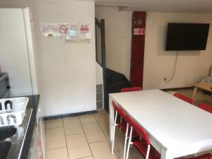 a kitchen with a white table and a tv in a room at Maison POUR OUVRIERS seulement PAS DE TOURISME, NI FAMILLE in Stains +12 photos