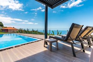 Un patio con dos sillas y una piscina. en Villa Pinheira III heated pool, en Calheta