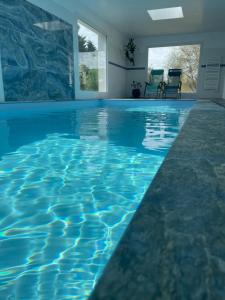 an infinity pool with blue water in a house at Plage à 300 m, piscine 29 degrés, 5 chambres, 4 sdb, calme in Bénodet
