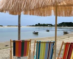 two chairs under a straw umbrella on a beach at Plage à 300 m, piscine 29 degrés, 5 chambres, 4 sdb, calme in Bénodet