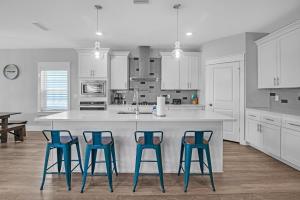 Una cocina con tres taburetes azules en una isla de cocina. en Pet Friendly Beach Retreat On 30A - Sleeps 14, en Santa Rosa Beach