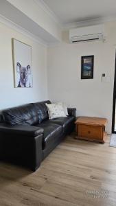 a black leather couch in a living room with a picture of a dog at Pelican Rise with a little surprise in Narngulu