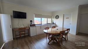 a living room with a table and a kitchen with a desk at Pelican Rise with a little surprise in Narngulu