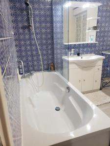 y baño con bañera blanca y azulejos azules. en Agréable maison avec vue panoramique, en La Bourboule