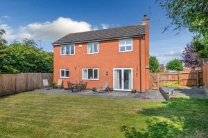 a red brick house with a patio in a yard at The Family & Contractor Haven in Shepshed