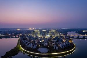 XintanHuangshan Tunxi Shangjiexing Riverview Resort Hotel的水上度假村的夜间鸟瞰图