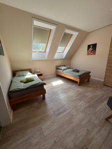 a bedroom with two beds and two windows at Herberge in der Orangerie auf dem Schlossgut Altlandsberg in Altlandsberg +5 photos