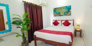a bedroom with a bed with red pillows and a plant at Corundum Twins in Arpora, 5 mins to Baga Calangute in Arpora