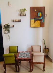 two chairs and a table in a room with a painting at Corundum Twins in Arpora, 5 mins to Baga Calangute in Arpora