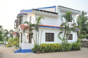 a white house with palm trees in front of it at Corundum Twins in Arpora, 5 mins to Baga Calangute in Arpora