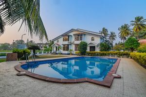a villa with a swimming pool in front of a house at Corundum Twins in Arpora, 5 mins to Baga Calangute in Arpora