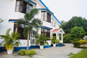 a white house with palm trees in front of it at Corundum Twins in Arpora, 5 mins to Baga Calangute in Arpora