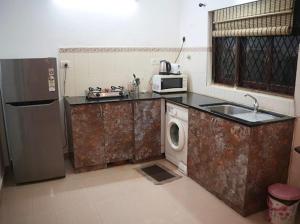 a kitchen with a washing machine and a microwave at Corundum Twins in Arpora, 5 mins to Baga Calangute in Arpora