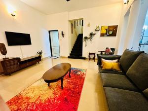 a living room with a black couch and a red rug at Corundum Twins in Arpora, 5 mins to Baga Calangute in Arpora