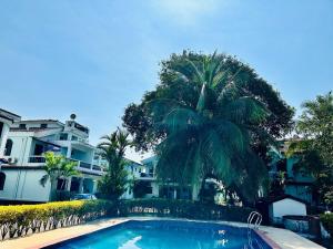 a palm tree and a swimming pool in front of a building at Corundum Twins in Arpora, 5 mins to Baga Calangute in Arpora